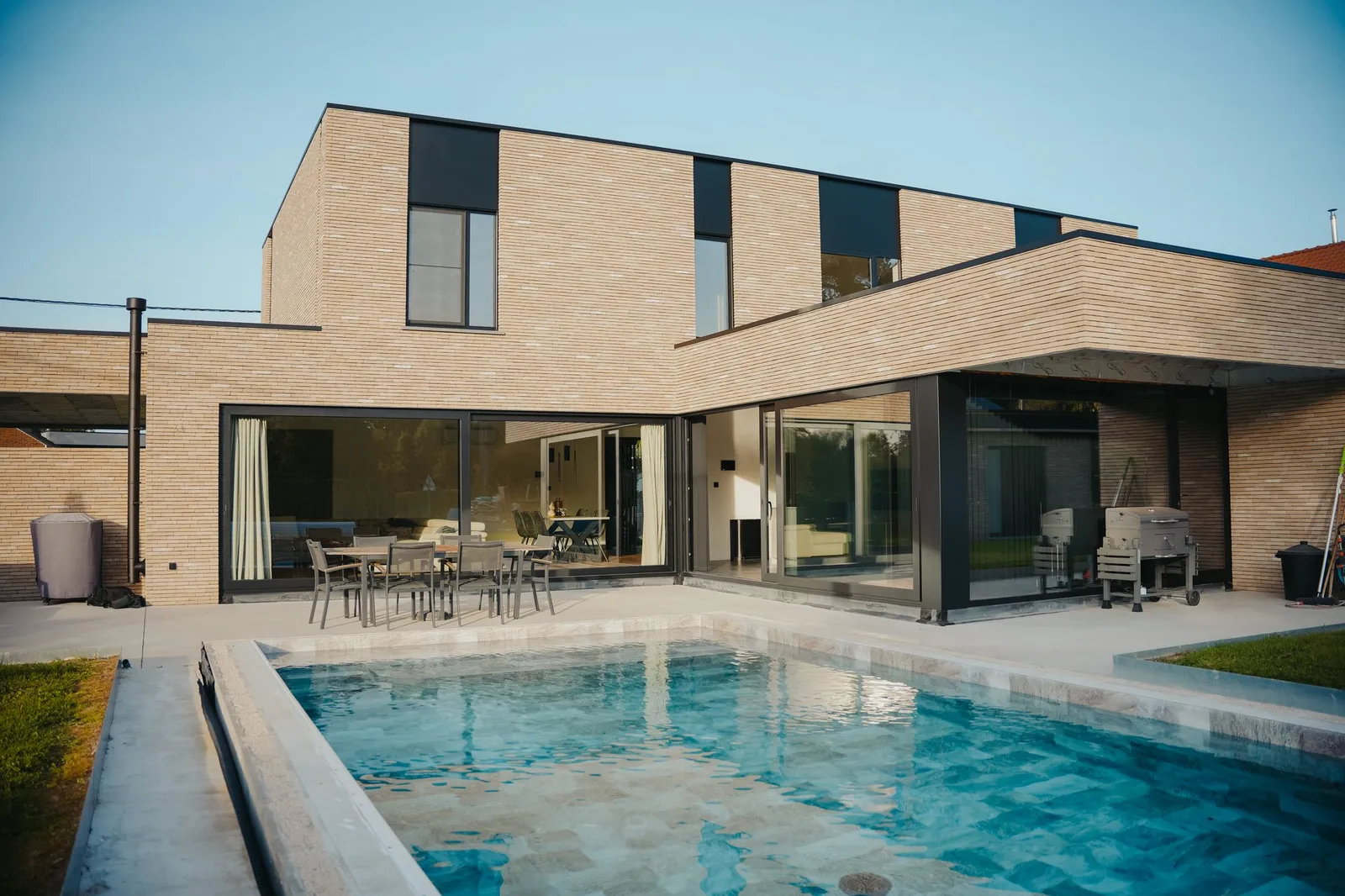piscine bleu-vert devant une maison contemporaine en briques aux grandes baies vitrées